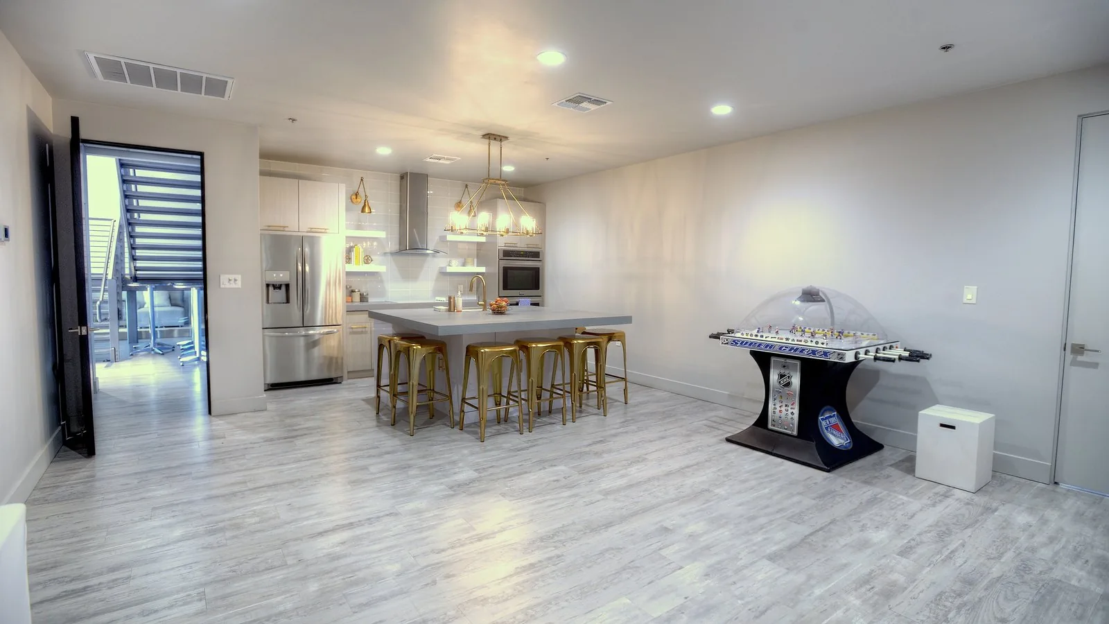 The full catering kitchen with island seating, gold stools, and a games area